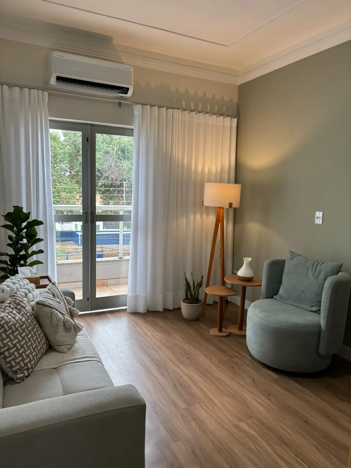 Sala ampla de atendimento com sofá, poltrona e sacada com luz natural